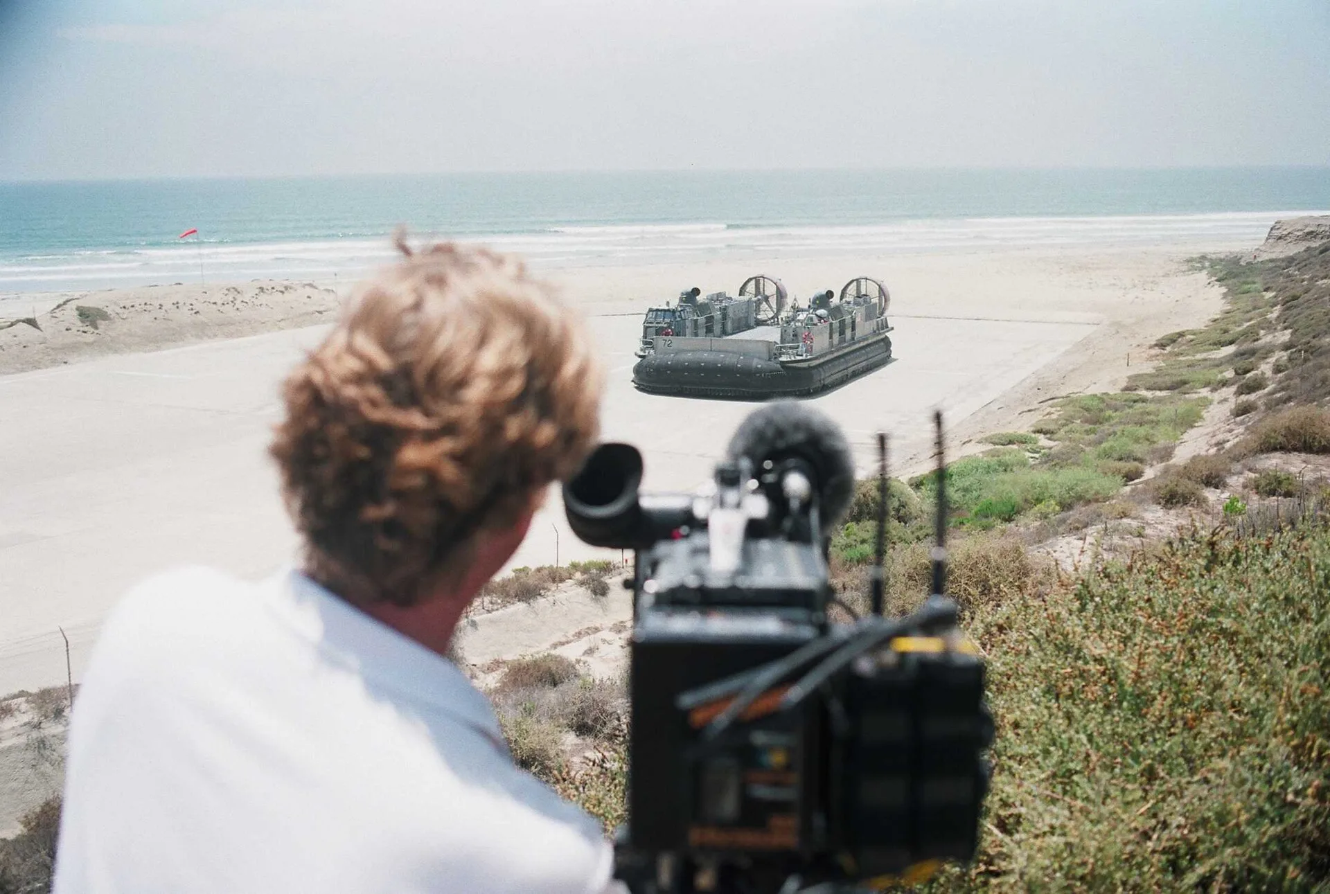 A videographer shoots a scene as a Landing Craft Air Cushion (LCAC) prepares to cross the surf during filming for a History Channel special to air in August. The series entitled, "Mail Call with Lee Ermey" will focus on explaining the vast complexities of military technology and the uniformed people. Copyright and music licensing for US videography client work, explained