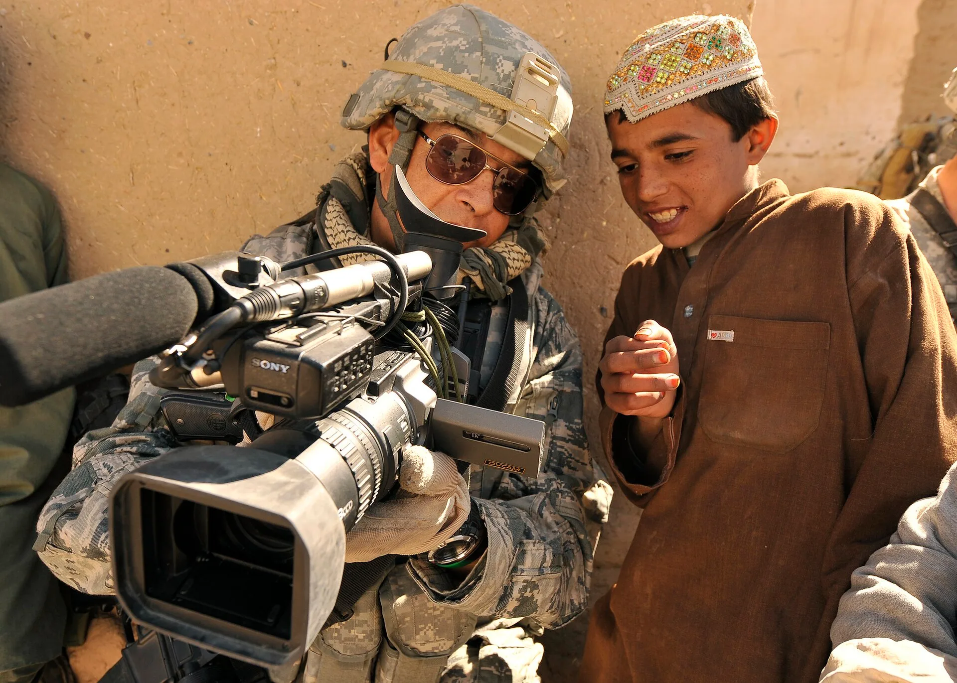 U.S. Air Force Master Sgt. Robert Carreon, a videographer with 4th Combat Camera who was attached to 5th Brigade, 2nd Infantry Division, shows an Afghan student his footage at the Bazaar school in Hutal, Afghanistan, Jan. 7, 2010. (U.S. Air Force photo by Staff Sgt. Dayton Mitchell) Related Photos a. Videography Startup: Buyers, Capacity and Positioning